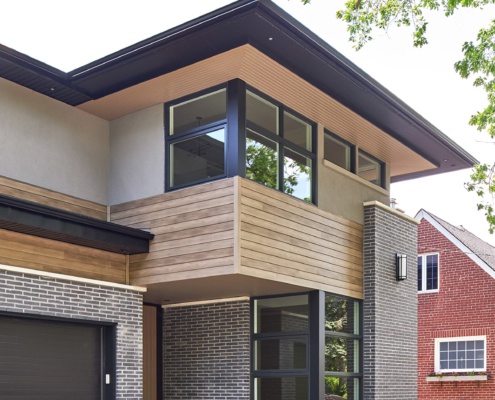 Modern house with corner window, black garage door and black frame windows.