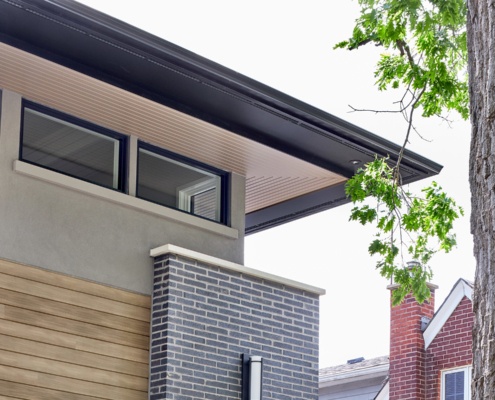 Mississauga home with black brick, black frame windows and wood soffit.