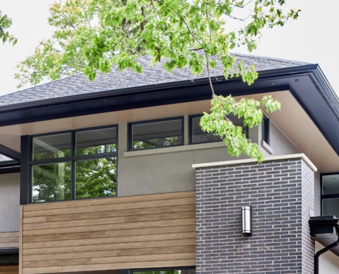 Modern home with wood siding, black frame windows and wood soffit.