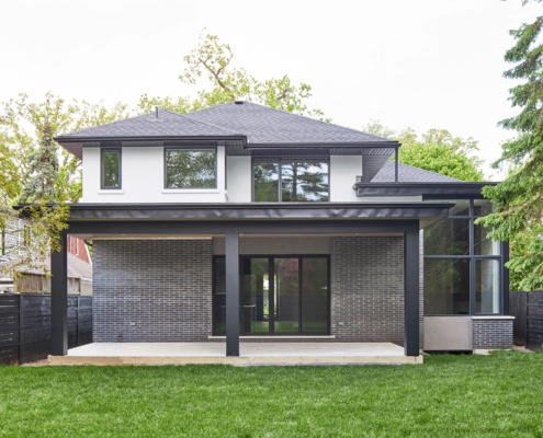 Backyard of modern home with brick, stucco siding and flat roof.