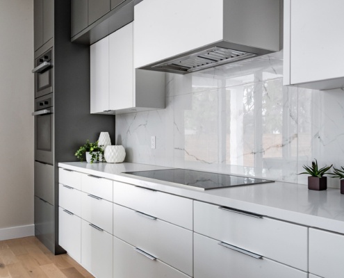 Modern kitchen with quartz countertop, double oven and tile backsplash.