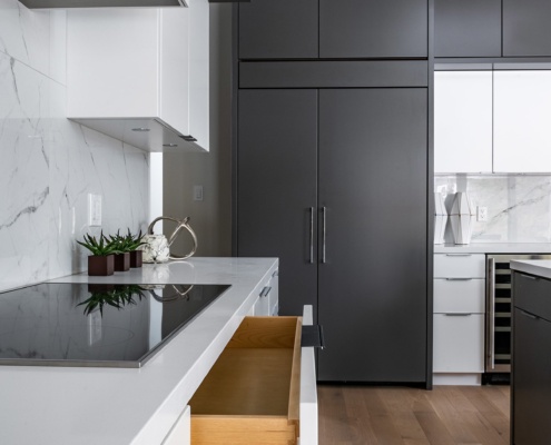 White kitchen with white drawers, hardwood floor and dark cabinets.