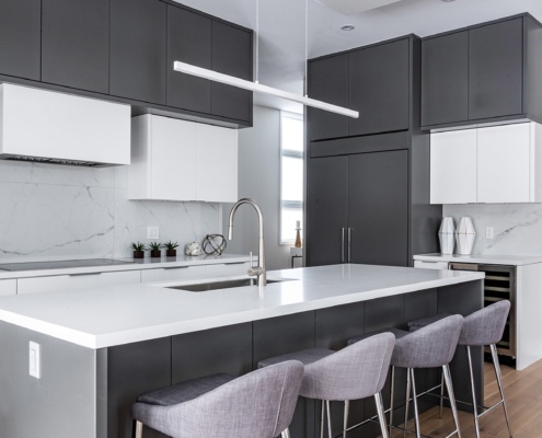 Elegant kitchen with dark cabinets, white backsplash and large island.