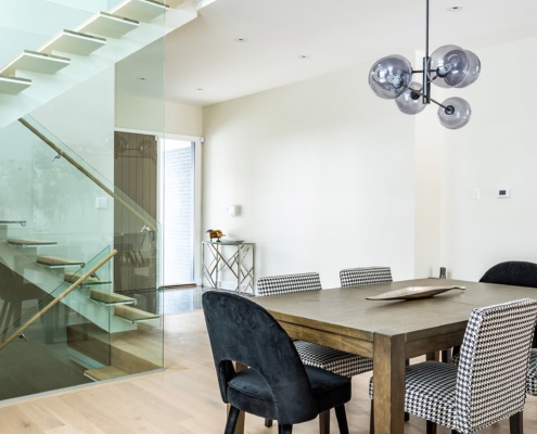 Mississauga dining room with modern chandelier, wood floor and glass stair.