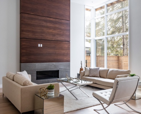 Family room with stone and wood fireplace, floor to ceiling window and wood floor.