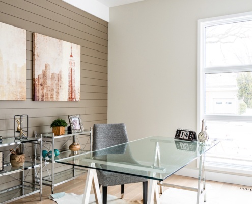 Modern home office with wood wall, white frame window and white baseboard.