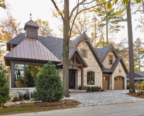 Traditional house with arched window, stone siding and stone driveway.