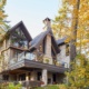 Stone house with glass railing, stone chimney and covered porch.