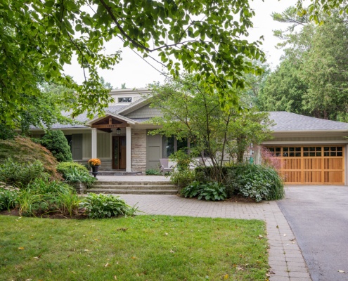 Custom home with wood garage door, white trim and stucco siding.