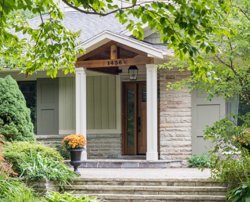 Renovation with stucco columns, stone siding and wood front door.