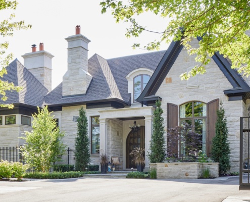 Toronto custom home with stone chimney, stone column and dark frame windows.