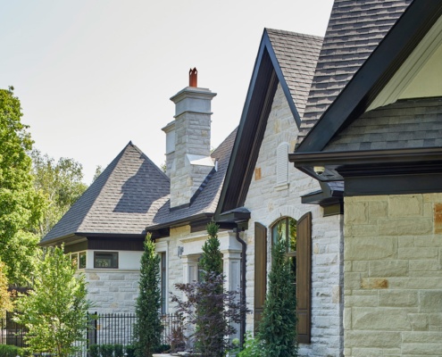 Traditional home with natural stone, wood shutters and dark trim.