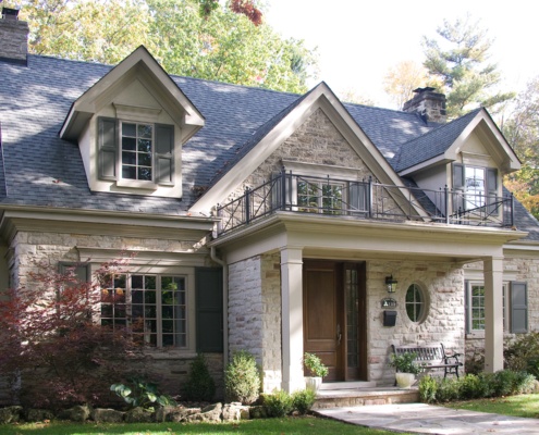 Traditional home with green shutters, gables and stone siding.