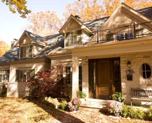 Home front exterior with natural stone, wood door and oval window.