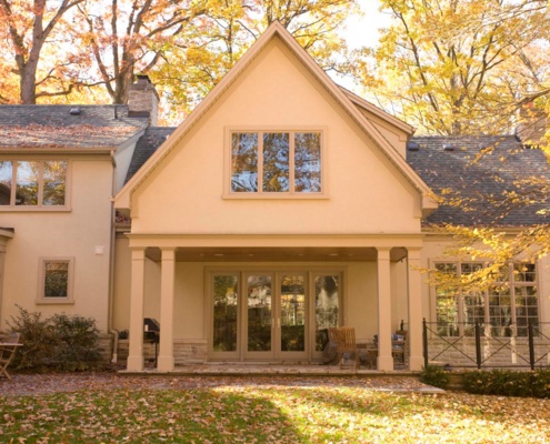 Rear exterior of home with stucco siding, covered porch and gabled roof.