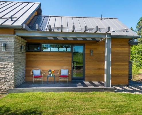 Cottage design with wood siding, stone siding and metal roof.