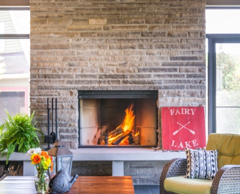 Cottage family room with stone fireplace, hardwood floor and black frame windows.