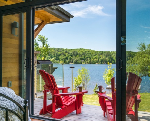 Master bedroom with ensuite deck, red muskoka chairs and large sliding glass door.