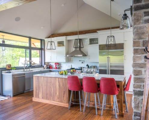 Large kitchen with white cabinets, large island and pendant lights.