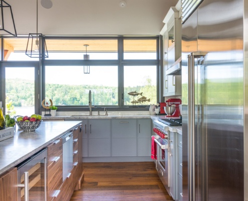 Modern kitchen with wood drawers, stainless steel fridge and black frame windows.