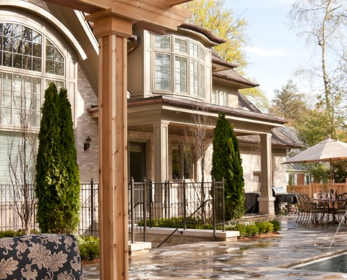 Chateau style home with arched window, stucco column and copper detailing.