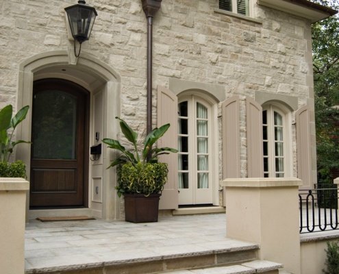 Stone house with wood door, beige shutters and copper eaves.