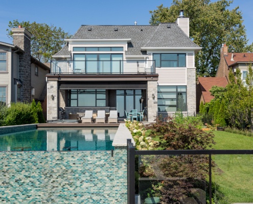 Transitional house with inground pool, wood siding and floor to ceiling windows.