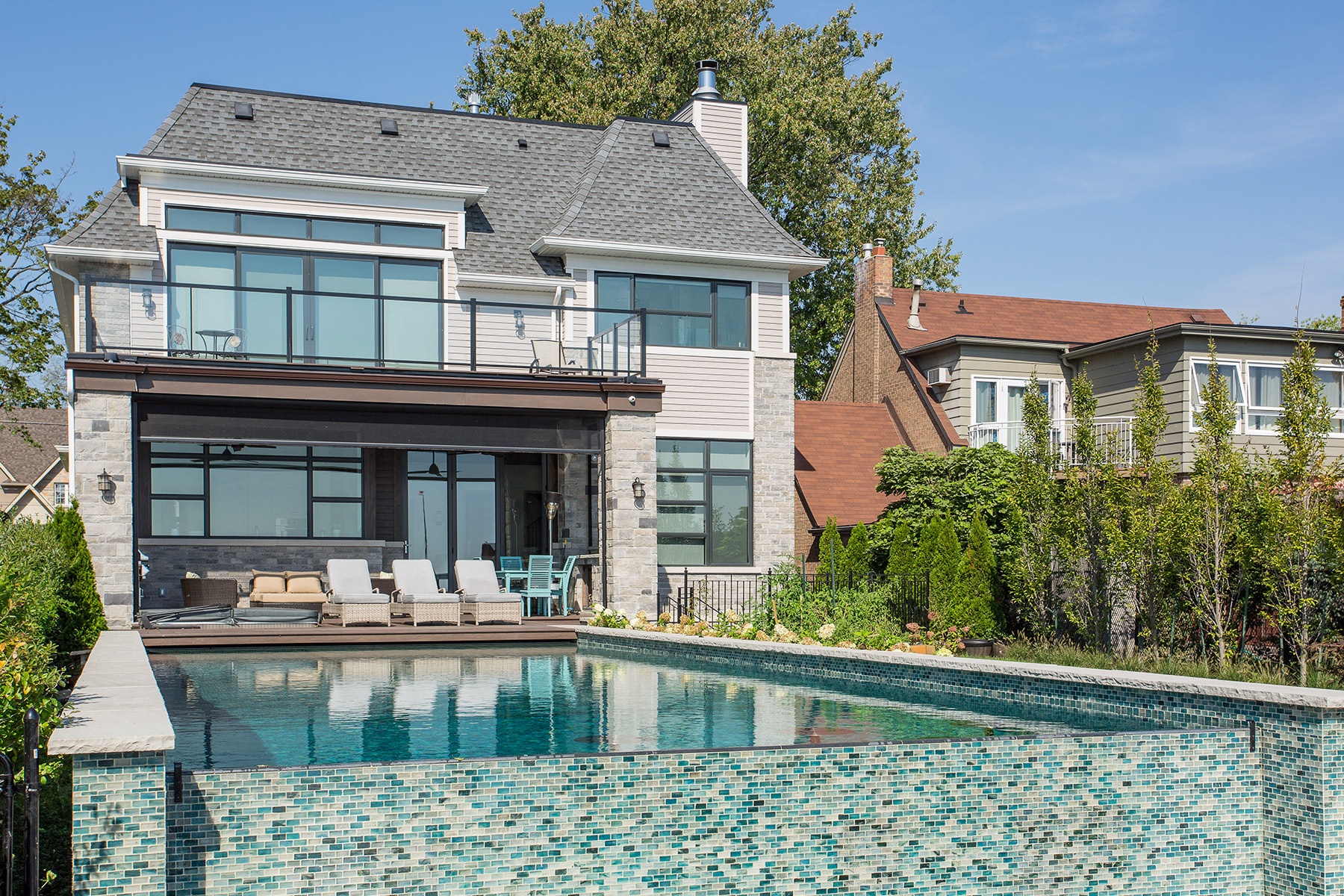 Mississauga custom home with natural stone, backyard pool and shingled roof.