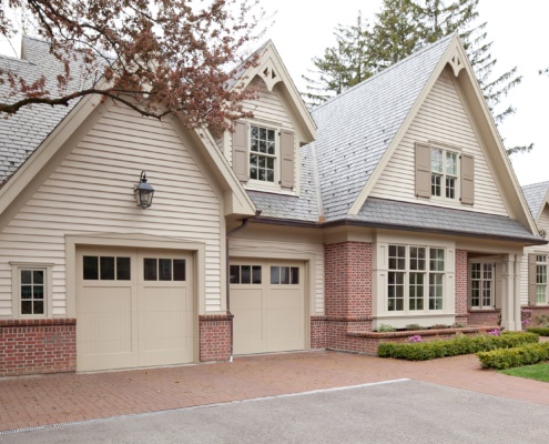 Custom home with beige garage doors, grid window and horizontal siding.