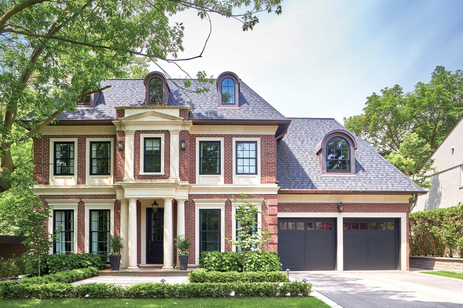 Traditional house with arched windows, brick and black frame windows.