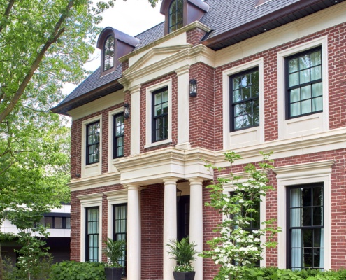 Traditional home with red brick, columns and black frame windows.