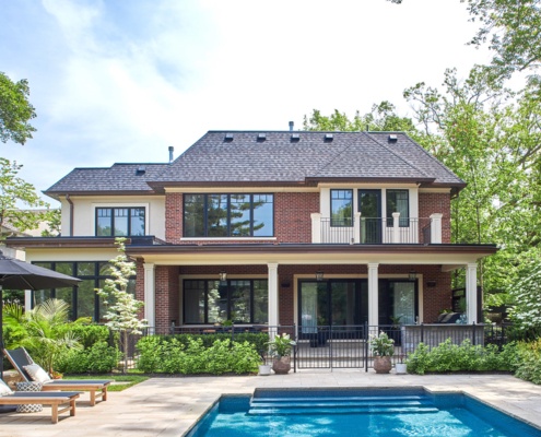 Georgian style architecture with black gate, covered porch and brown trim.