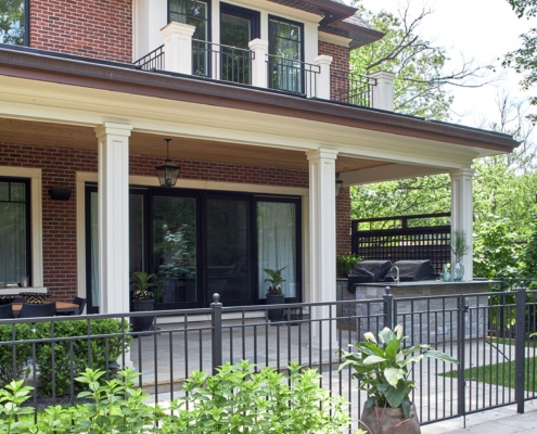 Traditional house with red brick, columns and second floor balcony.