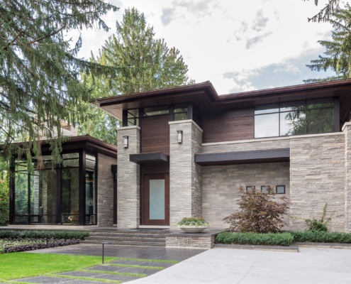 Natural modern house with black trim, floor to ceiling windows and natural stone.
