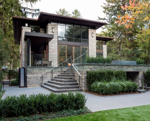 Home backyard with stone steps, outdoor dining and floating roof on modern home.