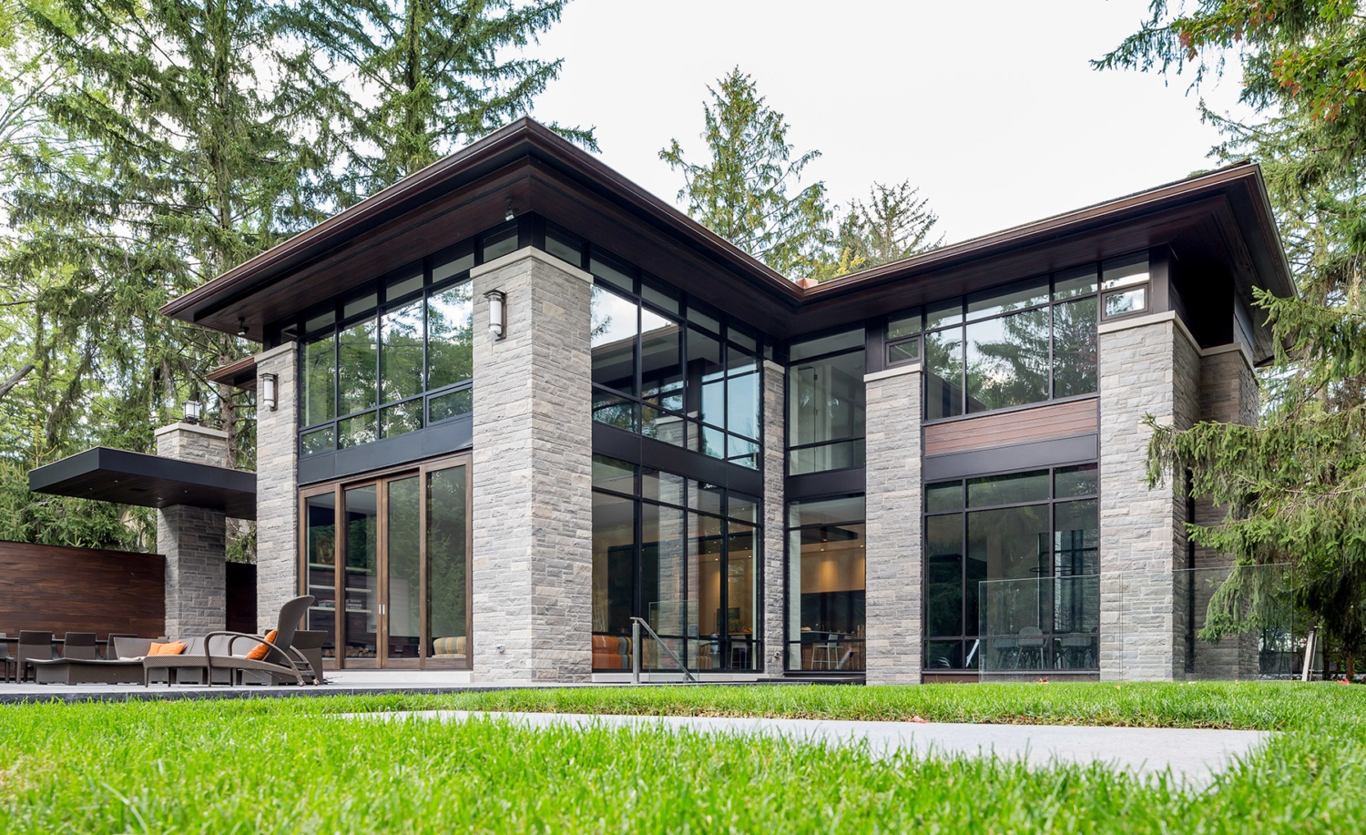 Modern home with large overhang, wood soffit, and stone columns.