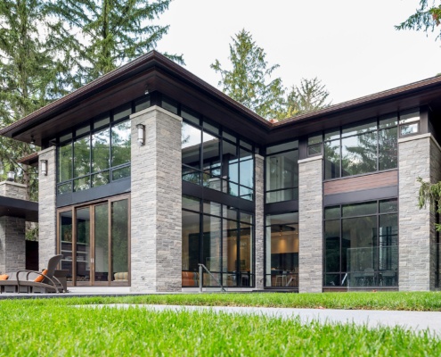 Modern home with large overhang, wood soffit, and stone columns.