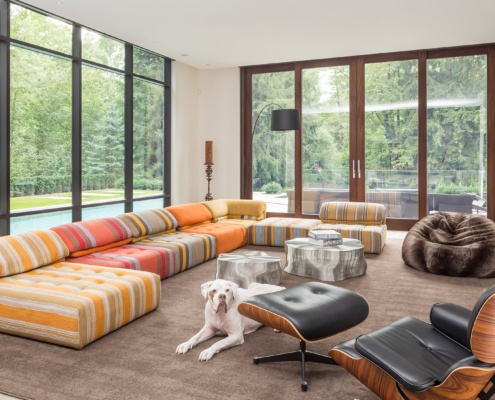 Living room with high ceilings, bean bag chair and floor to ceiling windows.