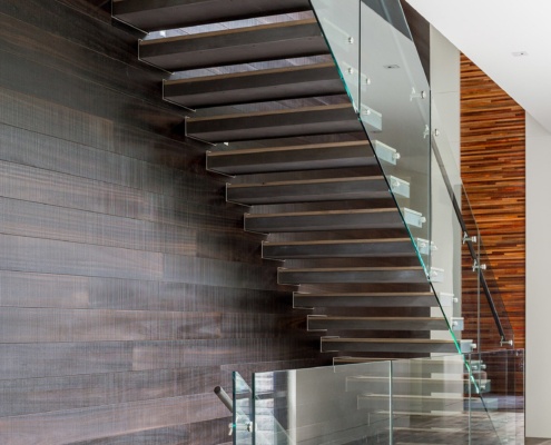 Floating stair with wood treads, glass railing and wood wall.