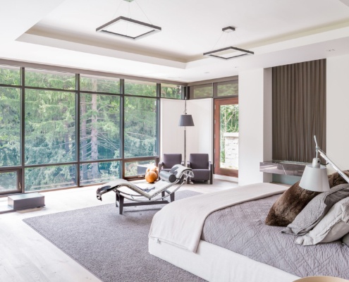 Master bedroom with floor to ceiling window, hardwood floor and white trim.