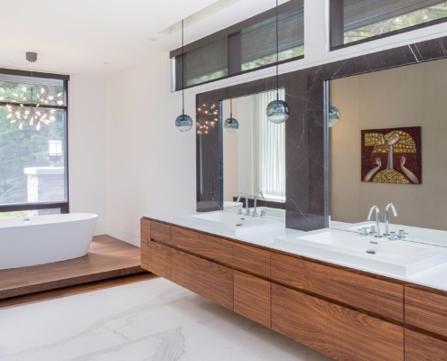 Modern bathroom with floor to ceiling window, wood trim and marble floor.