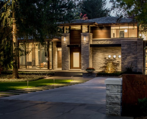 Modern home exterior with natural stone, floating roof and floor to ceiling glass.
