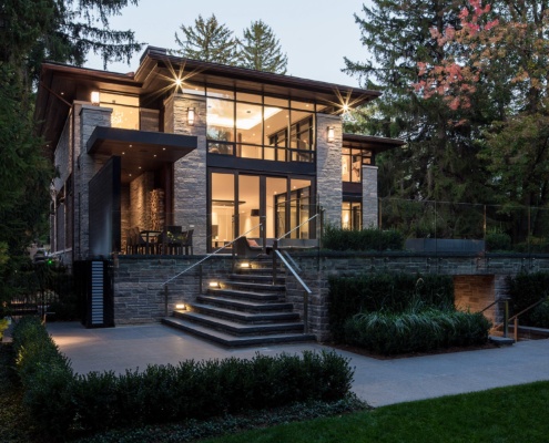 Modern patio with glass railing, retaining wall and scone lighting.