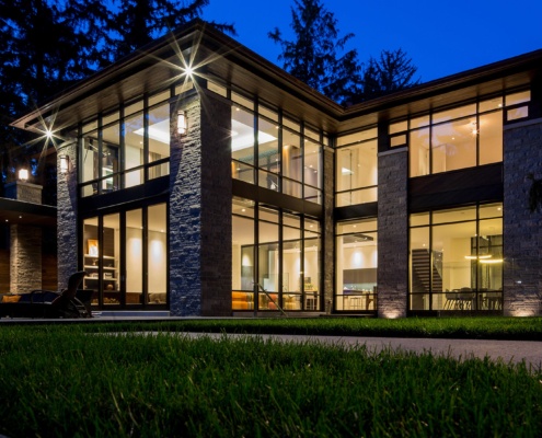 Modern exterior with flat roof, floor to ceiling windows, and stone columns.