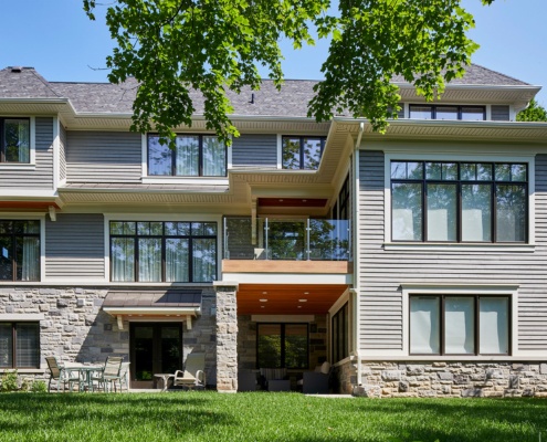 Traditional home with second floor deck, black frame windows and covered porch.