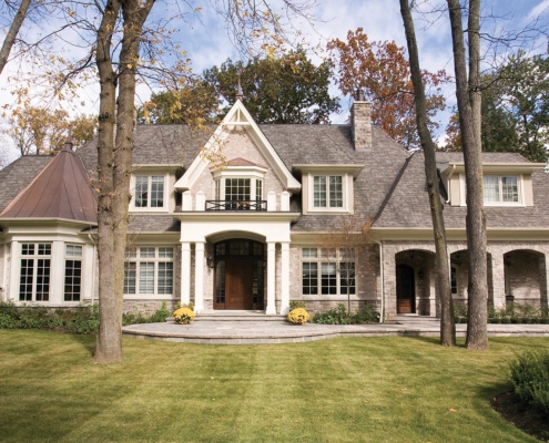 Traditional house design with stone chimney, grid windows and white trim.