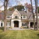 Traditional house design with stone chimney, grid windows and white trim.