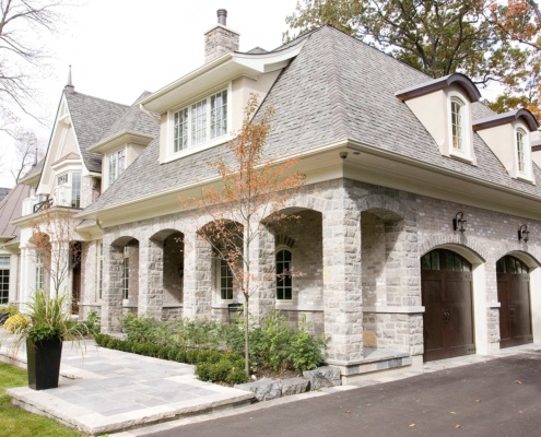 Stone house with stone archway, gabled windows and 3 car garage.