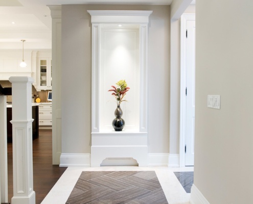 Home foyer with tile floor, wood staircase and white baseboard.