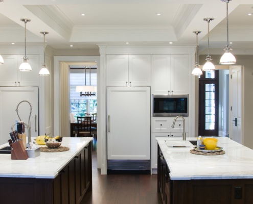 Kitchen with marble countertops, two islands and white cabinets.